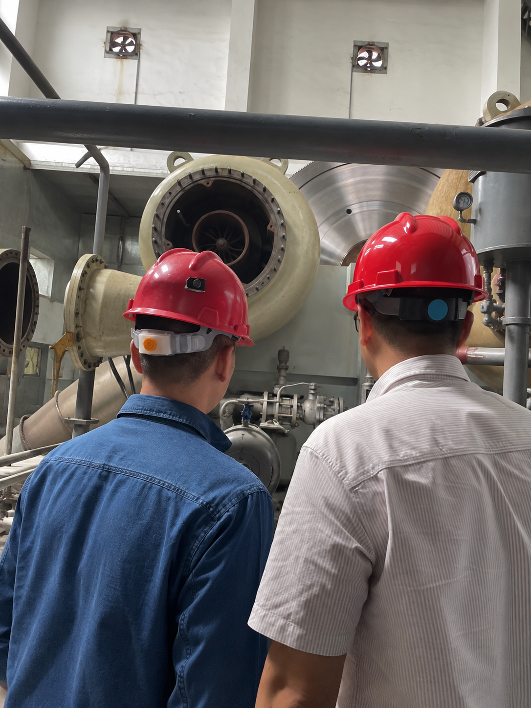 Helmeted personnel beside the opened compressor casing